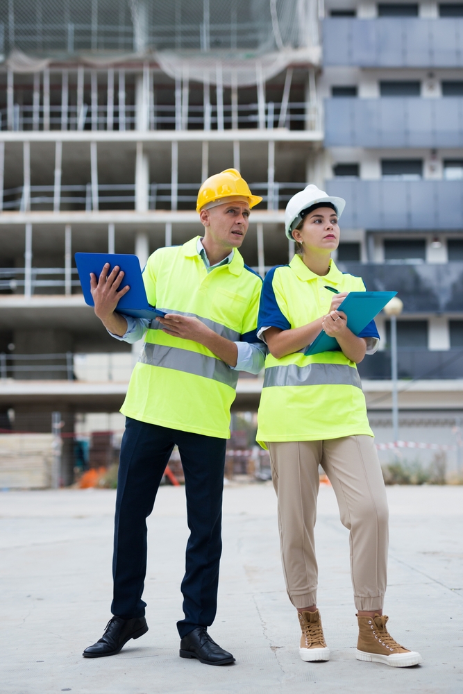 Two Qualified Engineers Working On A Construction Site Are Discussing